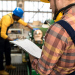 Inspetor industrial com prancheta verificando documentos de transporte de residuos em fabrica