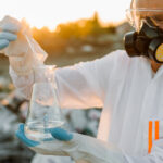 Ecologista em traje de proteção analisando amostra de produto químico tóxico — laudo de caracterização de resíduos industriais NBR 10005 10006