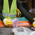 Trabalhador com luvas de proteção segregando resíduos industriais em esteira de classificação