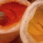 Pó de açafrão e pimenta em mercado, ilustrando matéria-prima de especiarias