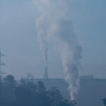 Chaminés industriais emitindo fumaça com poluição atmosférica ao fundo